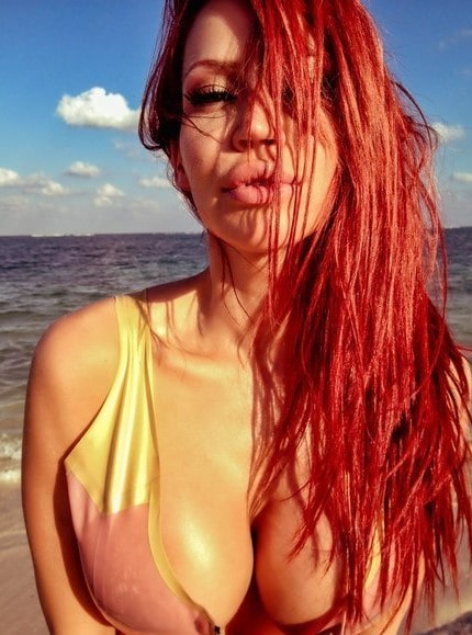 Instruktorka ogromnih grudi i crvene kose pozira na plaži u pocepanoj kratkoj majici