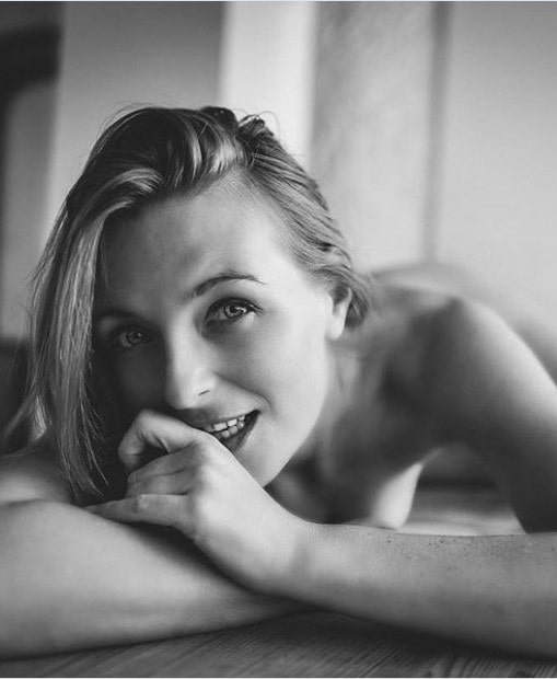 Fotograf, zgodna kovrdžava žena pozira gola na krevetu