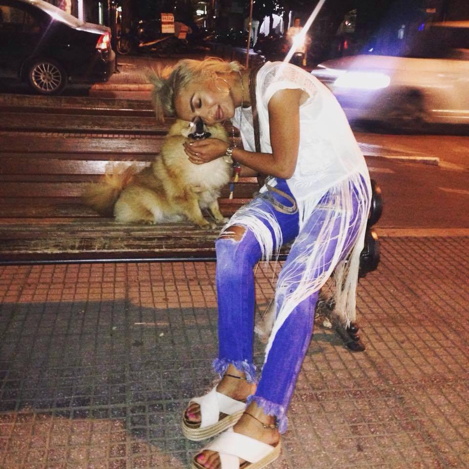 Smela, zgodna plavuša, vrlo sređena, pozira na ulici sa svojim psom