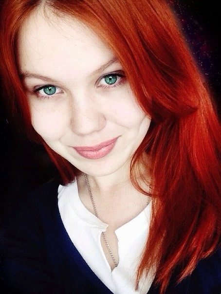 Mlada devojka crvene kose i zelenih očiju pozira nestašno