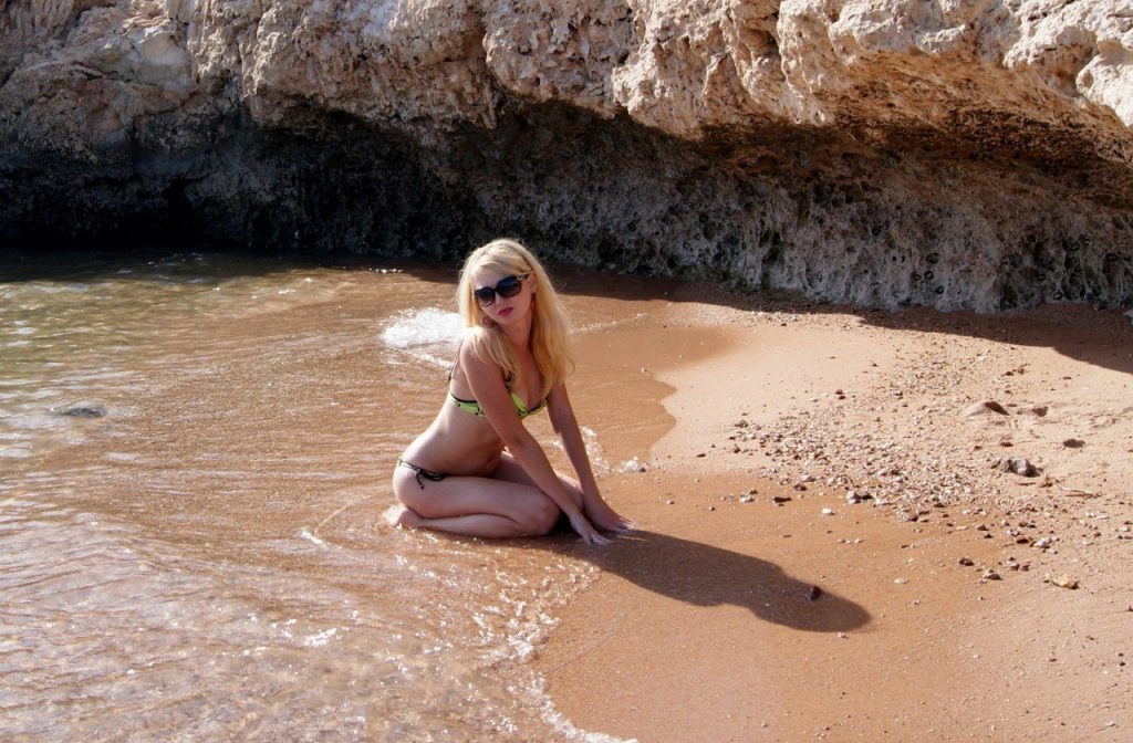 Dostupna za kuckanje, zgodna plavuša srednjih godina pozira u kupaćem kostimu na plaži